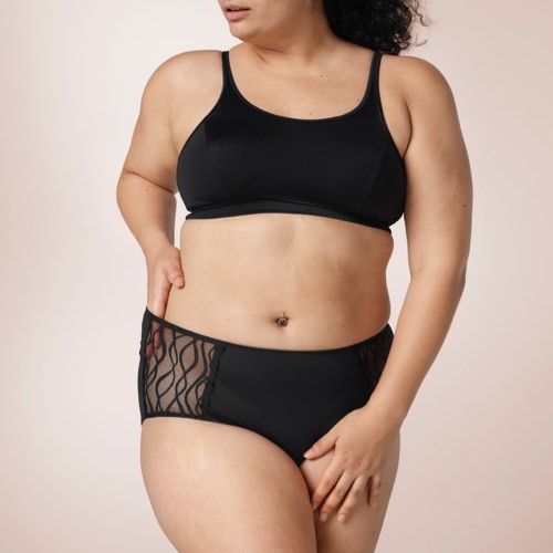 Woman wearing TENA Stylish washable underwear and showing off the lace details. 